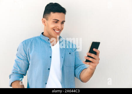 Outdoors Leisure. Stylish guy standing isolated on white having video call smiling cheerful Stock Photo