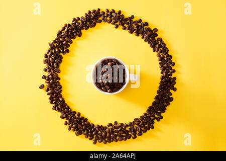 Cup of coffee in circle shape coffee beans on yellow background Stock Photo