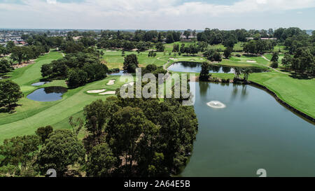 Aerial drone view Golf course fairway, water hazards, fountain, green with sand bunkers surrounded by trees Stock Photo
