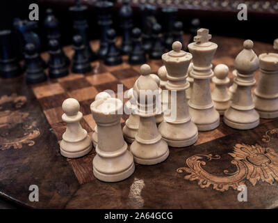 Old vintage white and black chess on wooden chessboard. Stock Photo