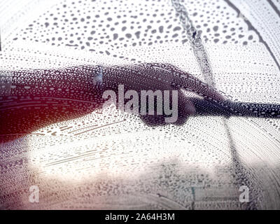 Windshield washing. Staff using squeegee cleaning the windshield, view from inside the car. Stock Photo