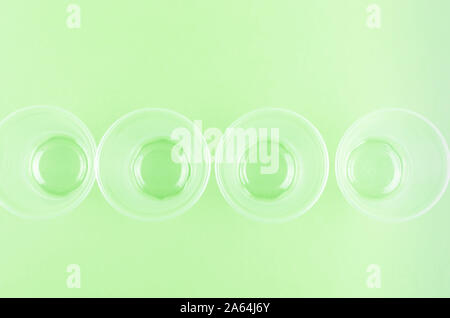 White Disposable cups, plates, forks, knives on light green background close-up - Environmental problem concept Stock Photo