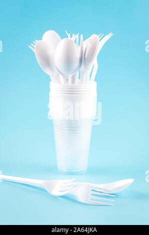 White Disposable cups, plates, forks, knives on light blue background close-up - Environmental problem concept Stock Photo