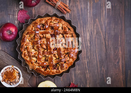 Traditional homemade pie with red apples and cinnamon on wooden table. Stock Photo