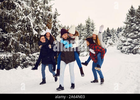 Playful men and women having fun in winter woods Stock Photo