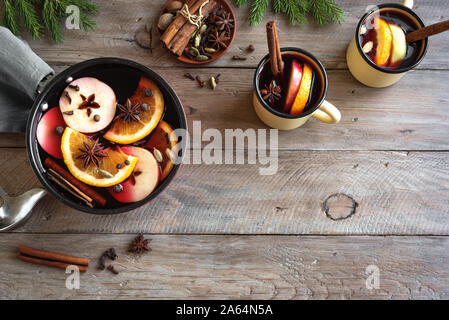 Mulled Wine for Christmas and winter holidays. Hot mulled wine drink with fruits and spices in casserole and mugs on wooden background, top view, copy Stock Photo