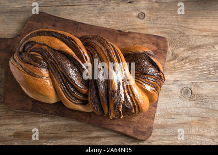 Chocolate Swirl Bread or Brioche Bread. Homemade sweet desert pastry - chocolate swirl bread (Babka) on wooden background, top view, copy space. Stock Photo
