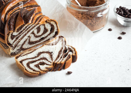 Chocolate Babka or Brioche Bread. Homemade sweet desert pastry - chocolate swirl bread, sliced on white background. Stock Photo
