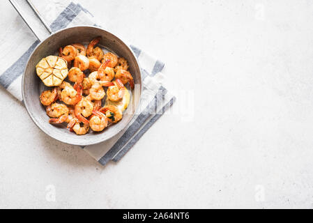 Roasted shrimps with lemon, garlic and herbs. Seafood, shelfish. Shrimps Prawns grilled with spices, garlic and lemon on white stone background, copy Stock Photo
