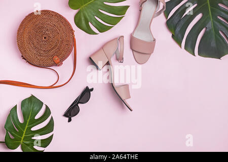 Stylish feminine summer accessories and monstera leaves on the pastel pink background, Stock Photo