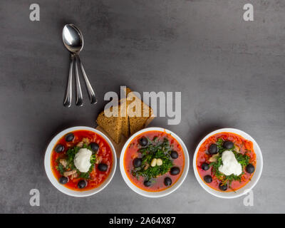 Ukrainian traditional borsch. Russian vegetarian red soup in white bowls on grey background. with black olives, garlic, lard, bread slices Top view. C Stock Photo
