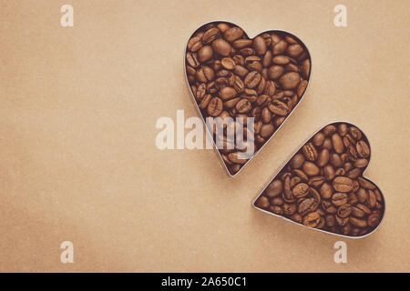 Heap of roasted coffee beans. Two hearts of coffee beans on neutral background. Mockup, layout with text space. Vintage brown parchment. Shape of hear Stock Photo