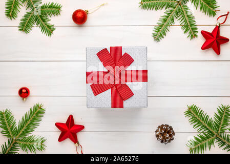 Christmas gift on white wooden surface surrounded with fir branches and Christmas decorations. Stock Photo
