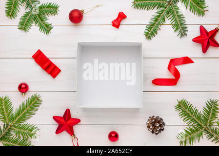 Empty, unpacked gift box surrounded with Christmas decorations, and piece of ribbon and bow. Mockup for product presentation. Stock Photo