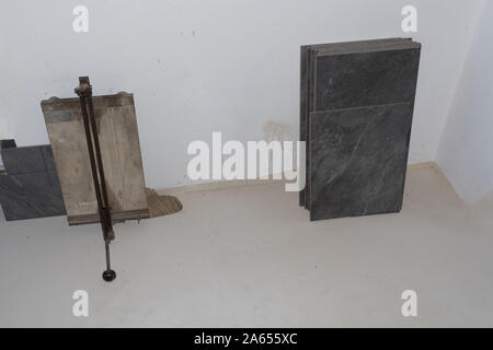Balcony floor tiles installation. Worker cutting tiles with porcelain tile cutter for porcelain tiles. Interior remodeling theme. Stock Photo