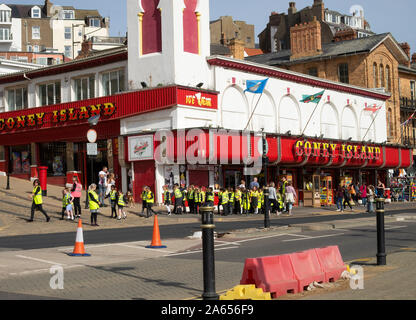 School Children in High Visibility Jackets in a Crocodile Walking Past Coney Island Amusement Centre in Scarborough North Yorkshire England UK Stock Photo