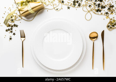 Christmas table setting with golden cutlery, decor and party decorations on white background. Top view. Xmas dinner. Stock Photo