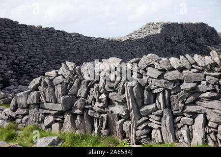 Ireland, County Galway, Aran Islands, Inis Mor: dry stone walls. In the background, Dun Duchathair (Black Fort) Stock Photo