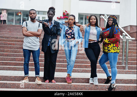 Group of five african college students spending time together on campus at university yard. Black afro friends studying. Education theme. Stock Photo