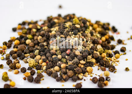 Pile of different types of peppercorns to season cooking recipes over white background Stock Photo