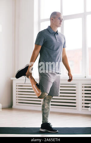 Young disabled man in sports clothing standing and exercising in the gym Stock Photo