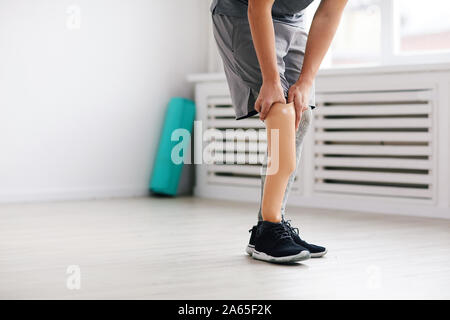 Close-up of young disabled man standing and wearing prosthesis on his leg in the room Stock Photo