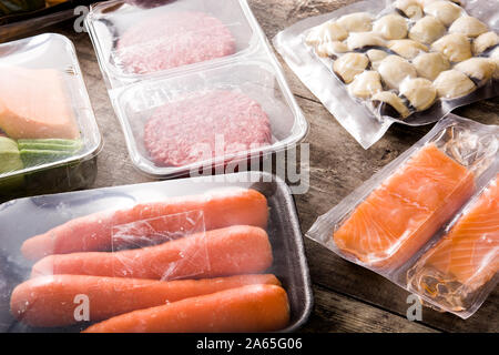 different types of packaged food. Meat, green beans, carrots and salmon on wooden table Stock Photo