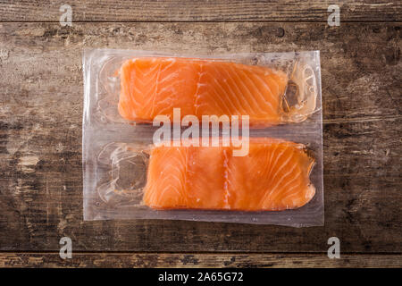 Salmon packaged in plastic on wooden table. Top view Stock Photo