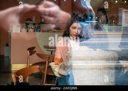 Moscow, Russia - September 14, 2019: Two girlfriends chatting at a cafe table. Women are sitting in a street restaurant. Cake on table. Tourism in the Stock Photo