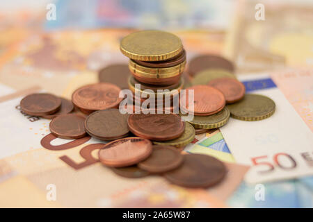 Many scattered euro coins and a column on a background of fifty and 20 euro bills Stock Photo
