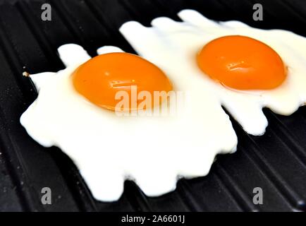 Two eggs frying on a griddle pan Stock Photo