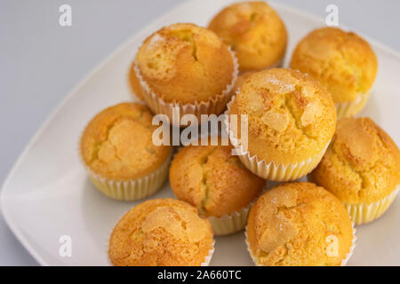 Delicious golden muffins covered with freshly baked sugar on a white square plate on a white background Stock Photo
