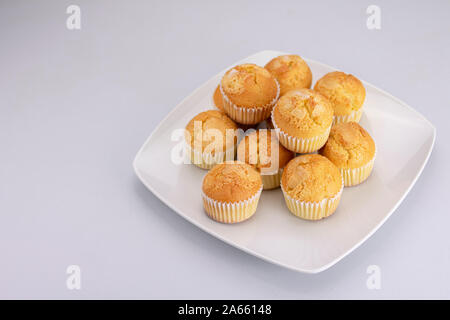 Delicious golden muffins covered with freshly baked sugar on a white square plate on a white background Stock Photo