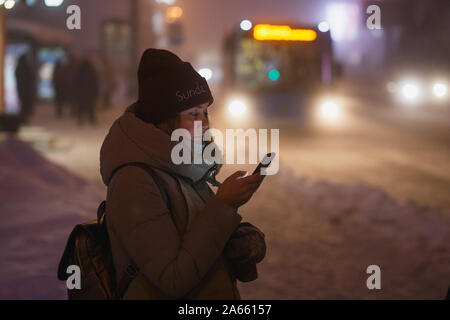 Checking the smartphone while waiting for the bus to come Stock Photo