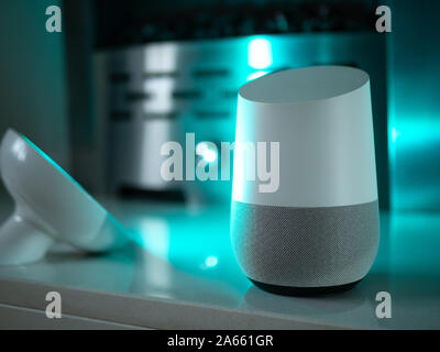 Smart home speaker device lit with colour changing LED lamp light - Aquamarine Stock Photo