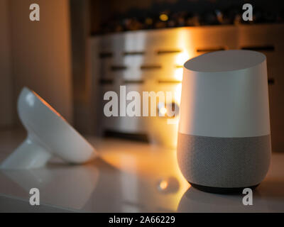 Smart home speaker device lit with colour changing LED lamp light - Yellow Stock Photo