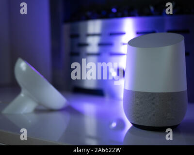 Smart home speaker device lit with colour changing LED lamp light - Purple Stock Photo