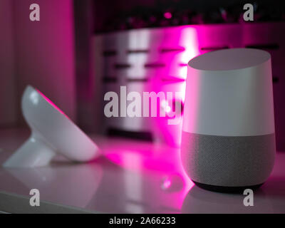 Smart home speaker device lit with colour changing LED lamp light - Pink Stock Photo