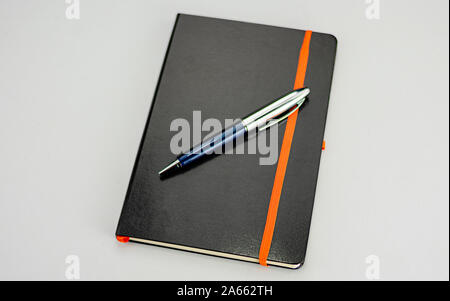Bound notepad with black hardcover and modern blue and silver pen Stock Photo