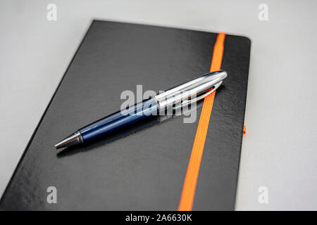Bound notepad with black hardcover and modern blue and silver pen Stock Photo