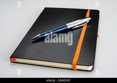 Bound notepad with black hardcover and modern blue and silver pen Stock Photo