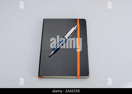 Bound notepad with black hardcover and modern blue and silver pen Stock Photo