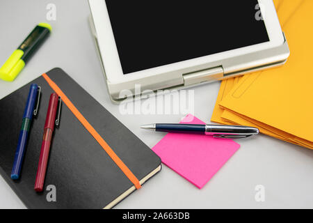 Office supplies consisting of tablet with keyboard, fluorescent marker, red and blue markers, modern pen, sticky notepad and note book Stock Photo