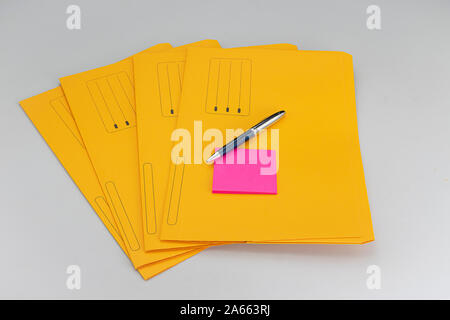 Modern ballpoint pen with fuchsia notepad on yellow subfolders on white background Stock Photo