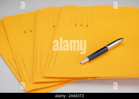 Office supplies consisting of a modern pen on yellow subfolders Stock Photo
