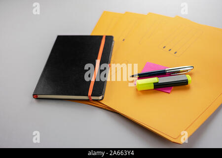 Pen and fluorescent marker on memo note, yellow subfolders and notebook Stock Photo