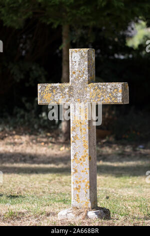 Ancient stone cross graveyard headstone. Religious monument gravestone in old English cemetery. Stock Photo