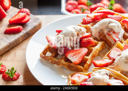 Strawberry waffles. Sweet dessert preparation. Serving with home-made ice cream. Delicious mouth-watering food on white plate. Naughty but nice meal c Stock Photo