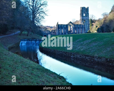 View of Fountains Abbey, North Yorkshire, England, from a path beside the River Skell in the Studley Royal Water Gardens on a frosty morning Stock Photo