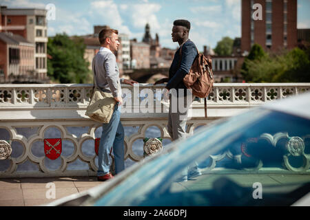 Two businessmen having a chat on a bridge in York. They are facing each other. Stock Photo